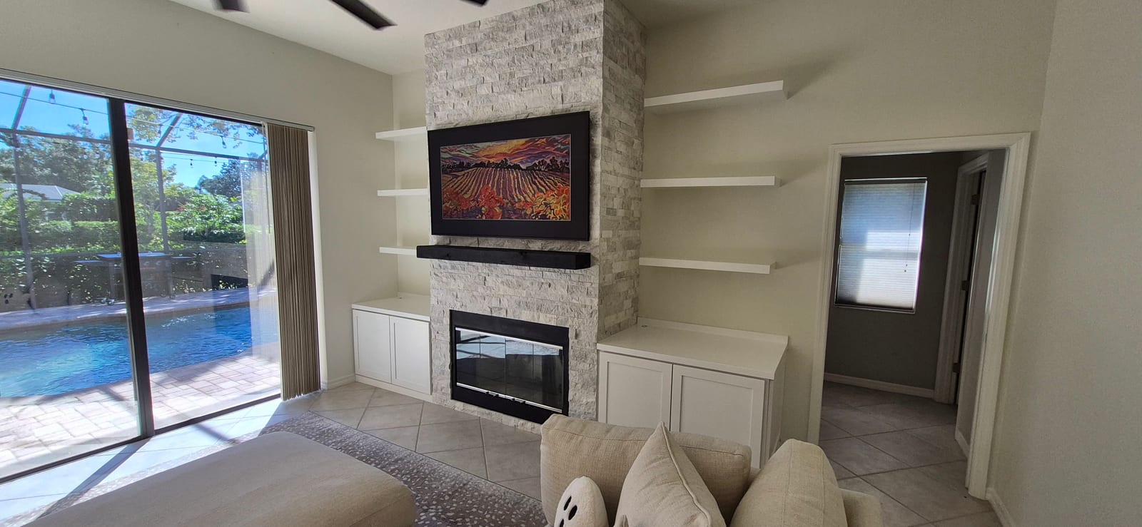 Stone fireplace flanked by white built-in cabinets and floating shelves